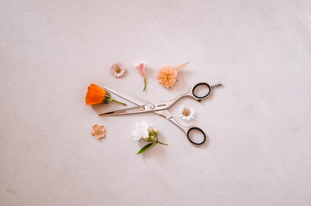 nozyczki fryzjerskie wsród kwiatków na białym tle