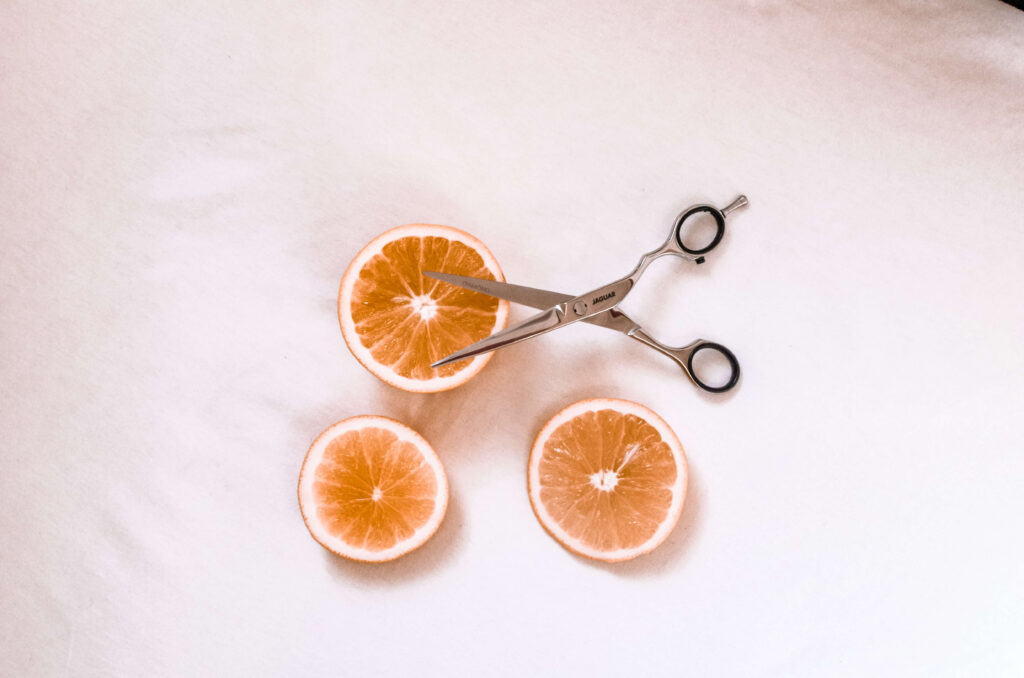 nożyczki fryzjerskie z pomarańczą na białym tle