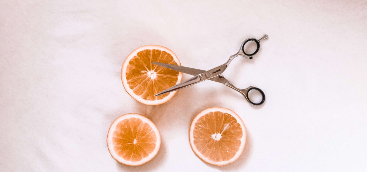nożyczki fryzjerskie z pomarańczą na białym tle